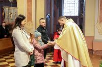 Ksiądz przyjmuje dary eucharystyczne od rodziny